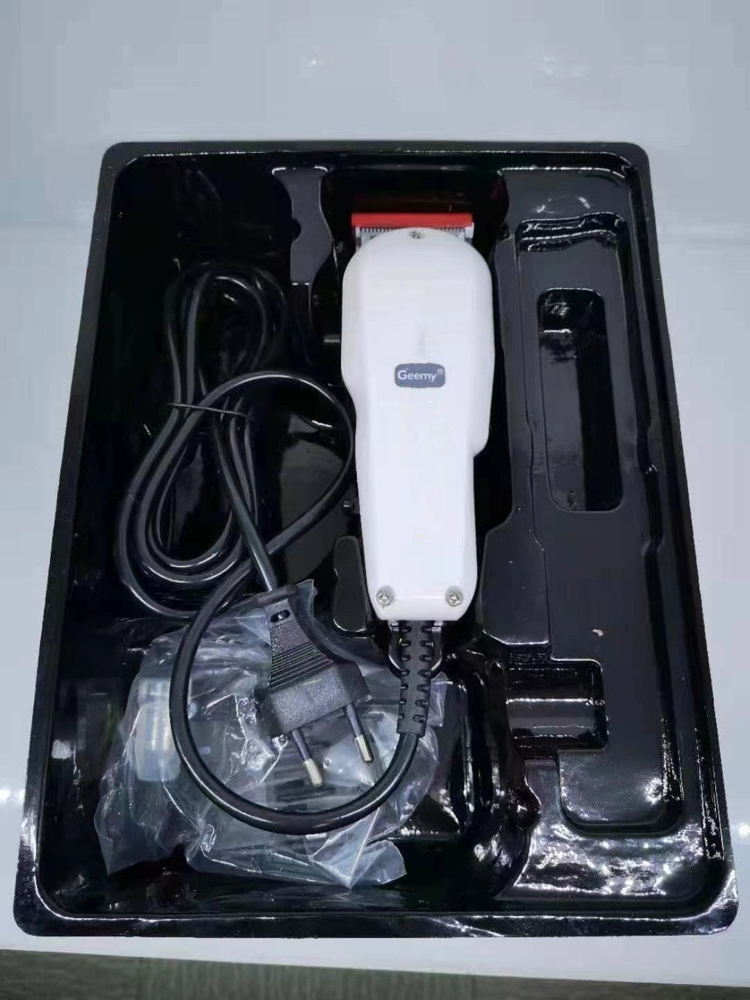 GEEMY GM-1017 rechargeable cordless hair clipper in a black tray with charging cable and accessories