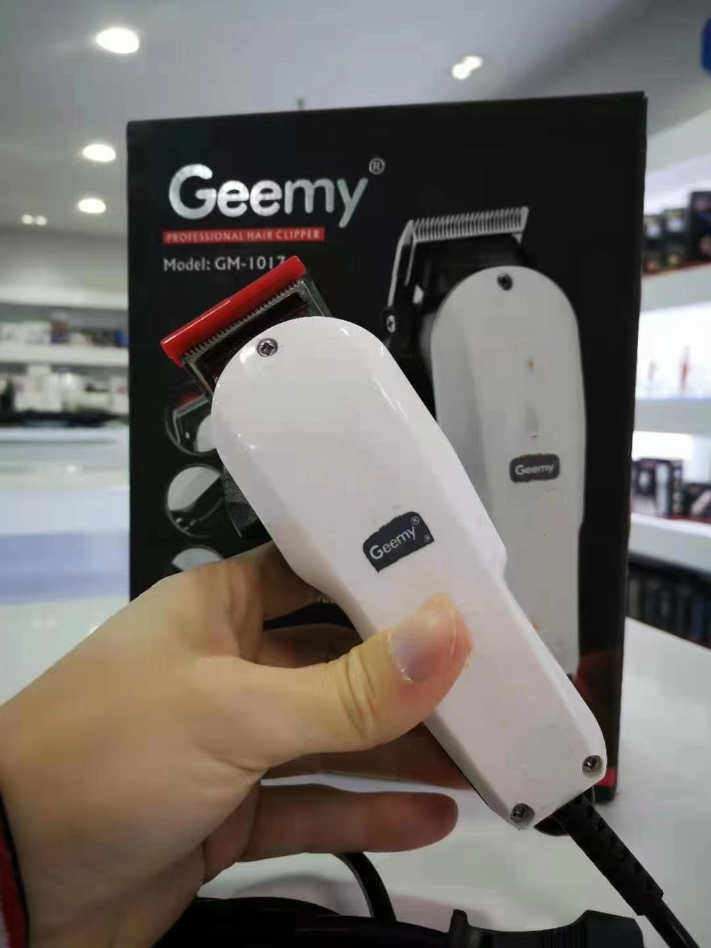 White GEEMY GM-1017 hair clipper held in front of its retail packaging