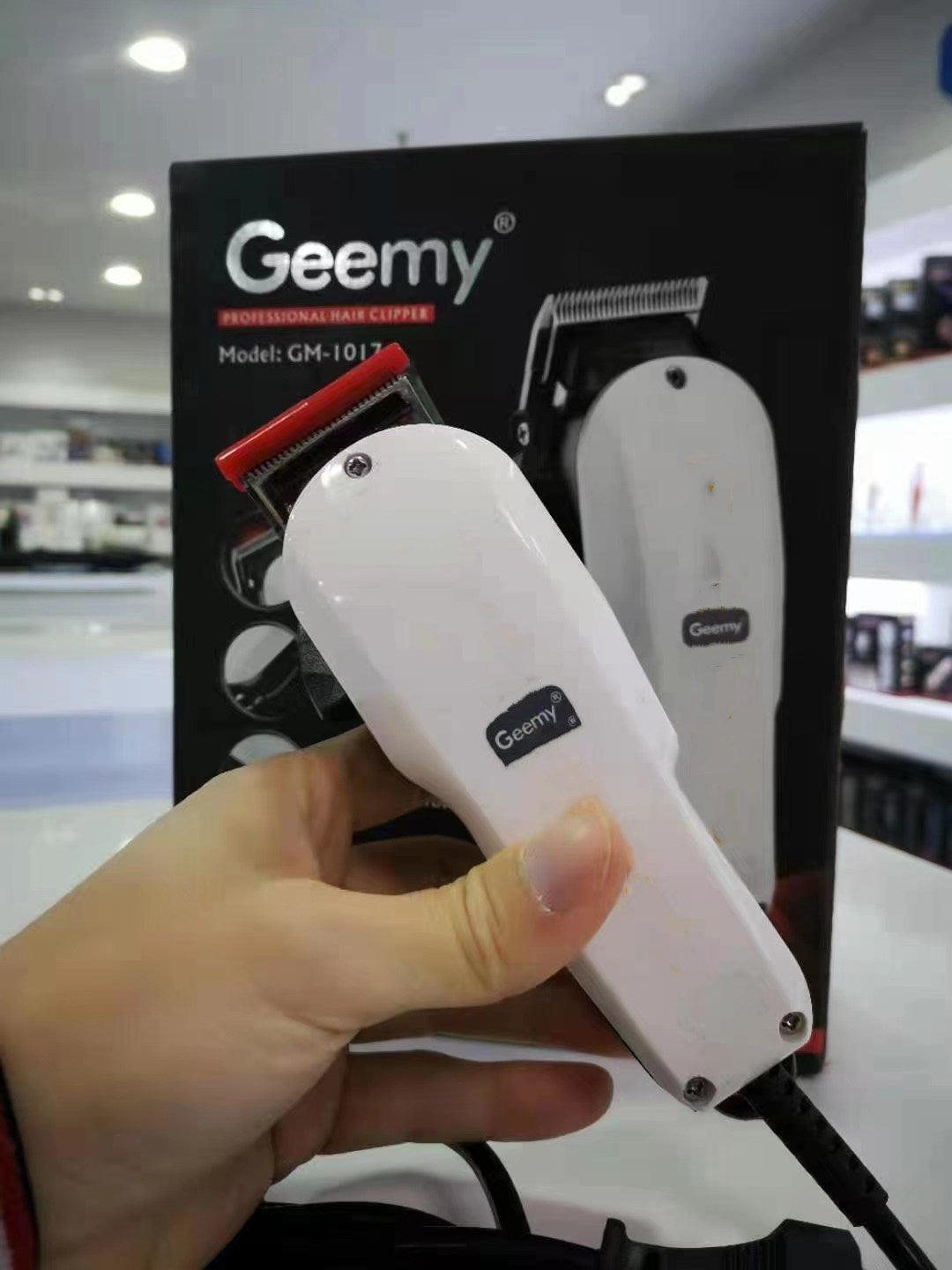 White GEEMY GM-1017 hair clipper held in front of its retail packaging